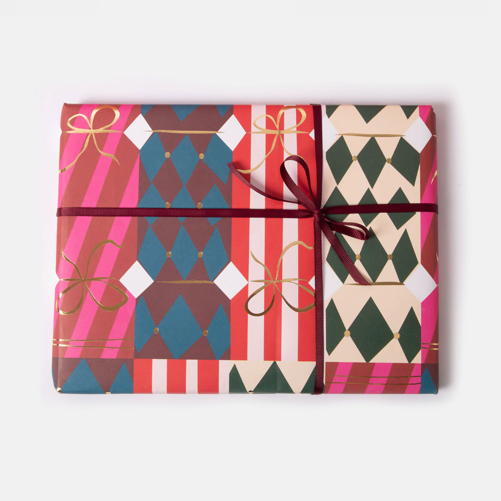 Wrapped present with colourful patterned christmas cracker print wrapping paper and ribbons on a white background