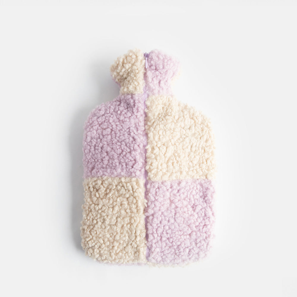 hot water bottle with a synthetic borg cover in a lilac and cream check design and a zipped closure