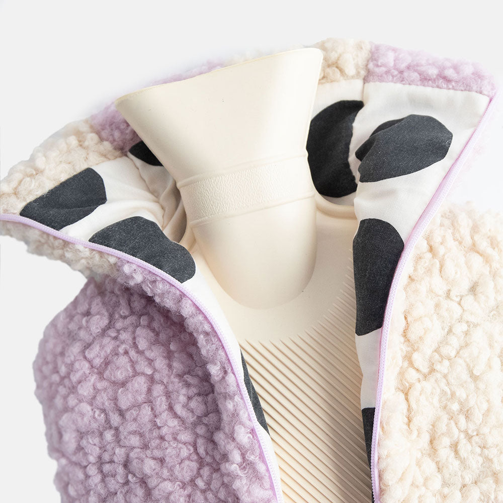 hot water bottle with a synthetic borg cover in a lilac and cream check design with a monochrome spot lining and zipped closure