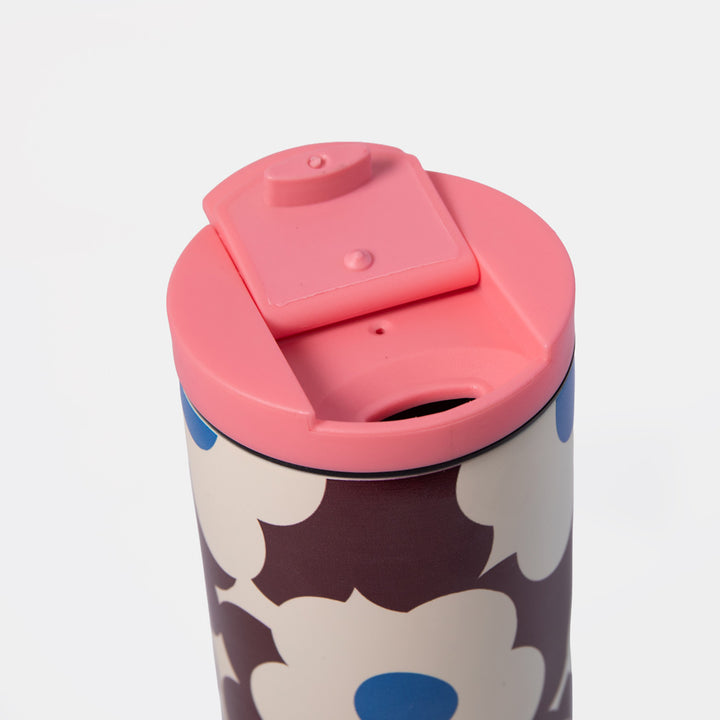 A close-up of a travel mug with a pink lid and a floral pattern featuring dark brown, cream, and blue flowers.