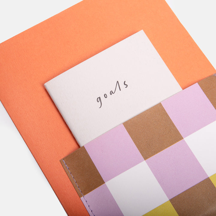 journaling set with an orange main journal with colourful front pocket containing a mini 'goals' notebook