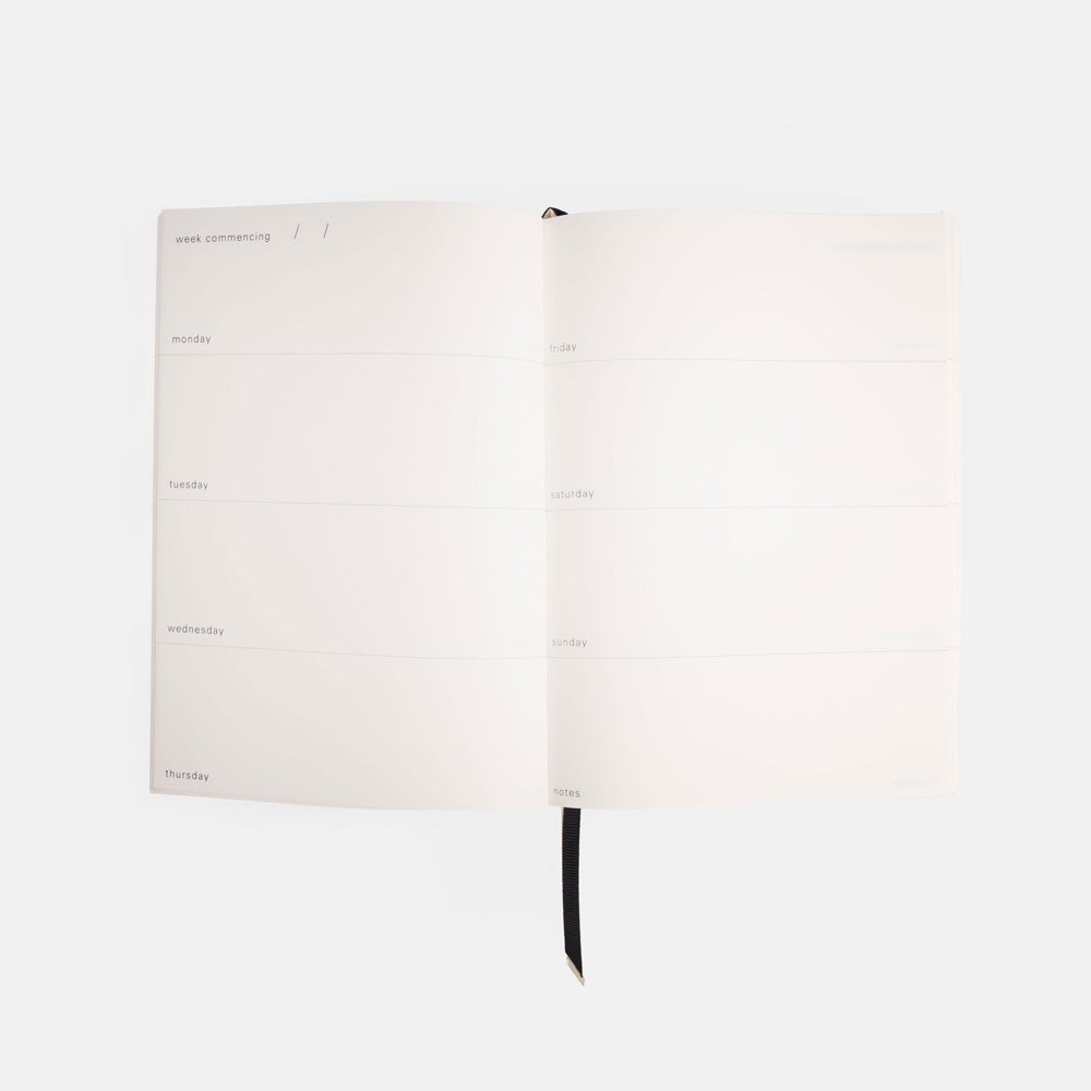 White weekly journal with black binding on a white background