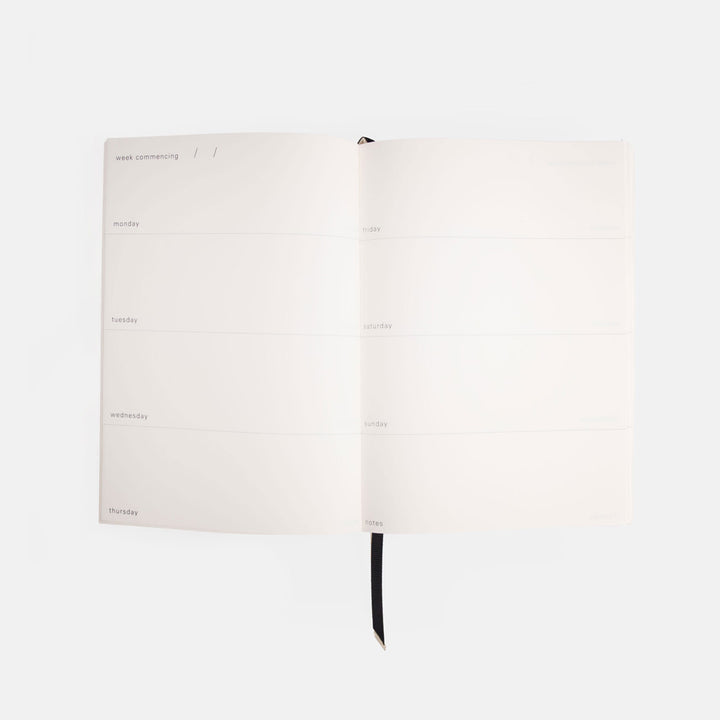 White weekly journal with black binding on a white background