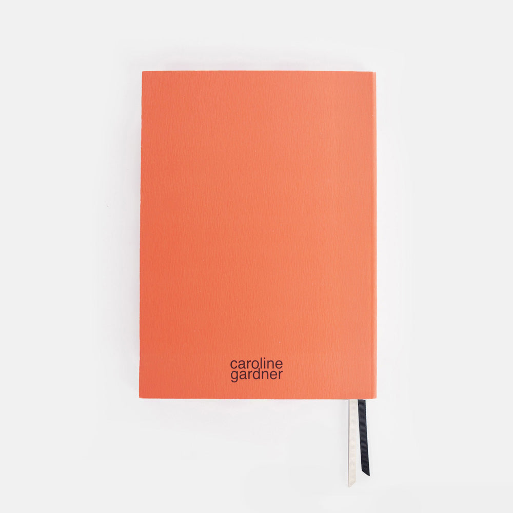 Orange journal with 'caroline gardner' branding on a white background