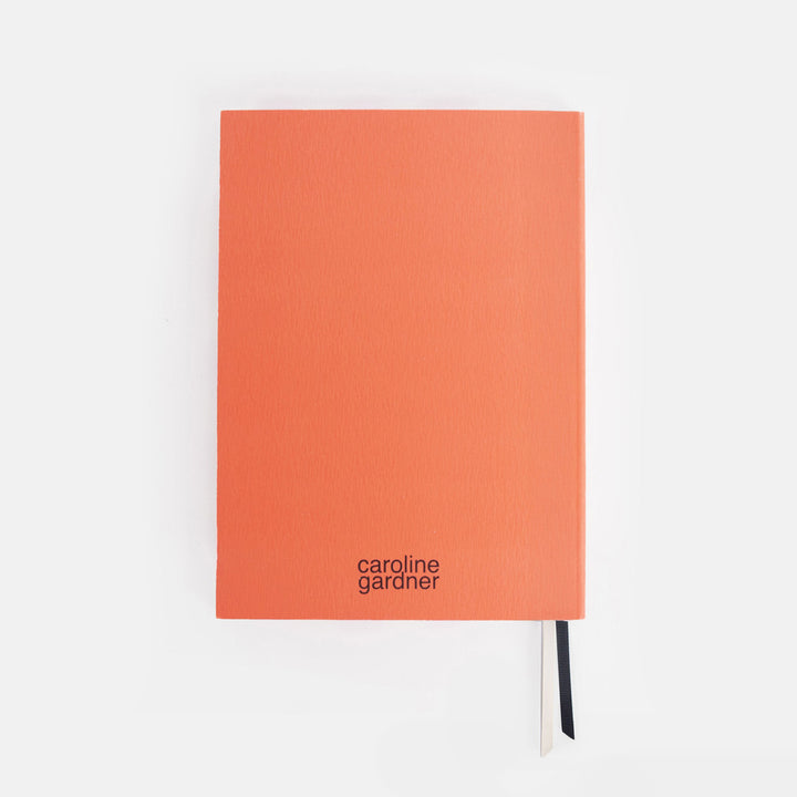 Orange journal with 'caroline gardner' branding on a white background