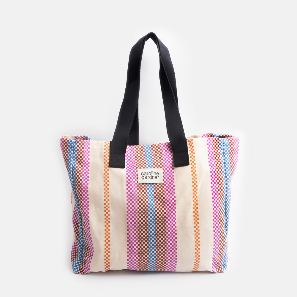 multi coloured checkerboard stripe large tote bag with black handles and 'caoline gardner' branded tab