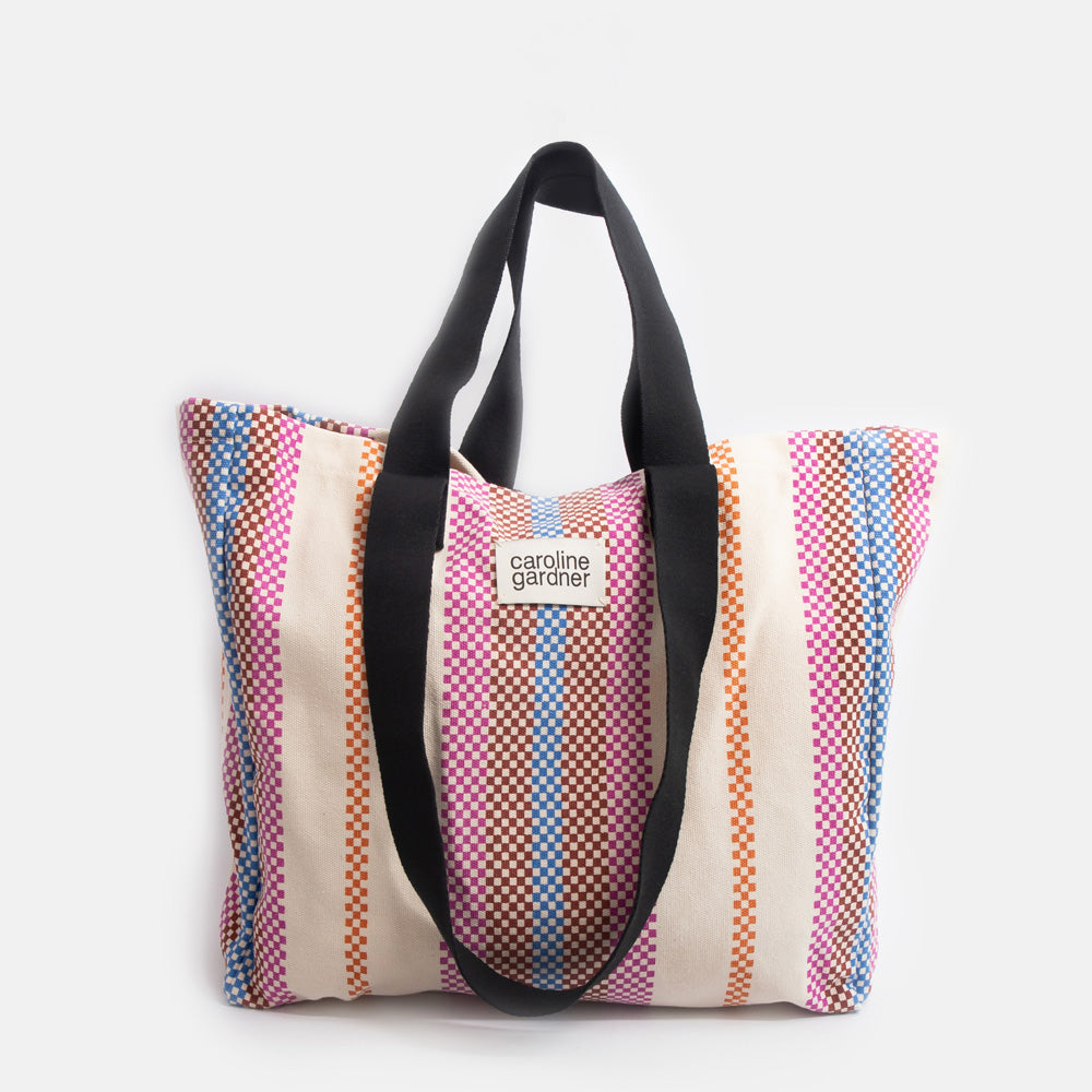 multi coloured checkerboard stripe large tote bag with black handles and 'caoline gardner' branded tab