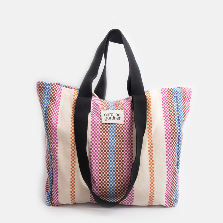 multi coloured checkerboard stripe large tote bag with black handles and 'caoline gardner' branded tab