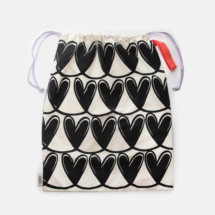 Drawstring laundry bag with black heart pattern on a white background