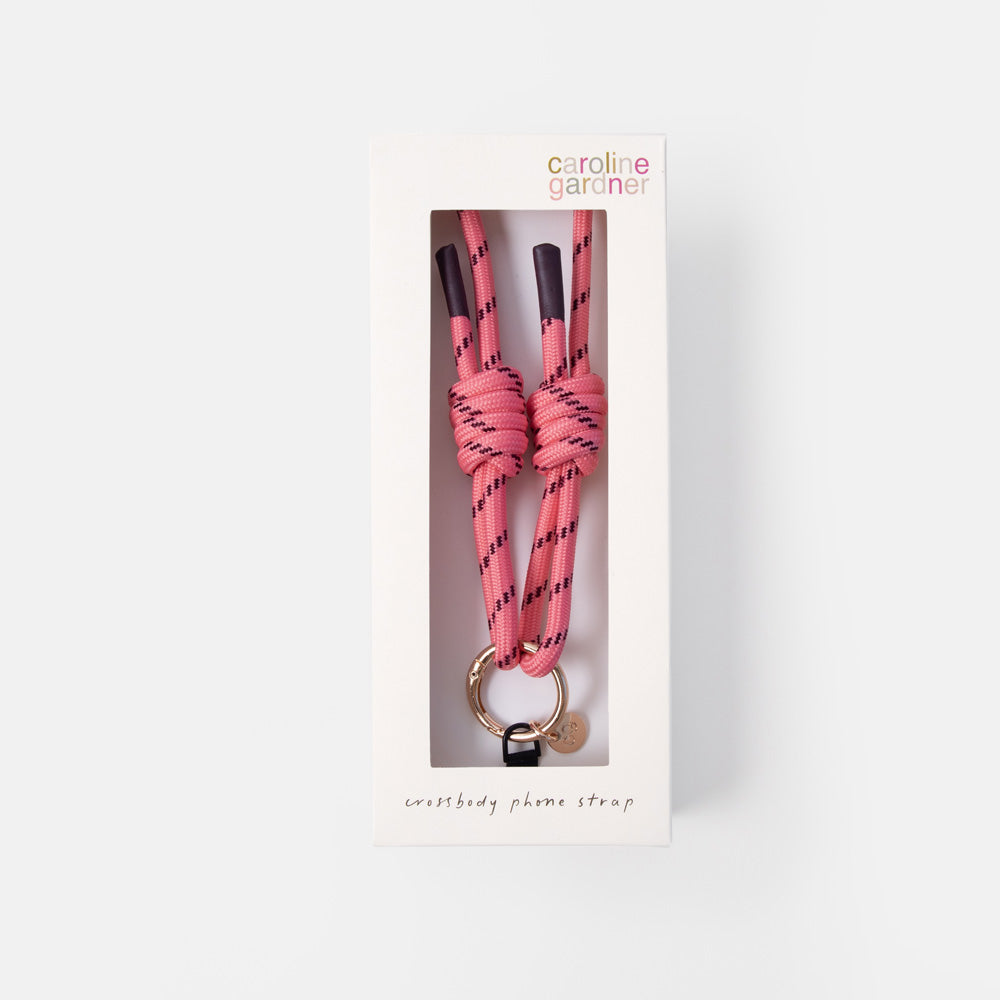 Caroline Garder Phone Strap in pink and black patterned cord with a gold-tone ring, shown in its white retail packaging box against a light gray background.