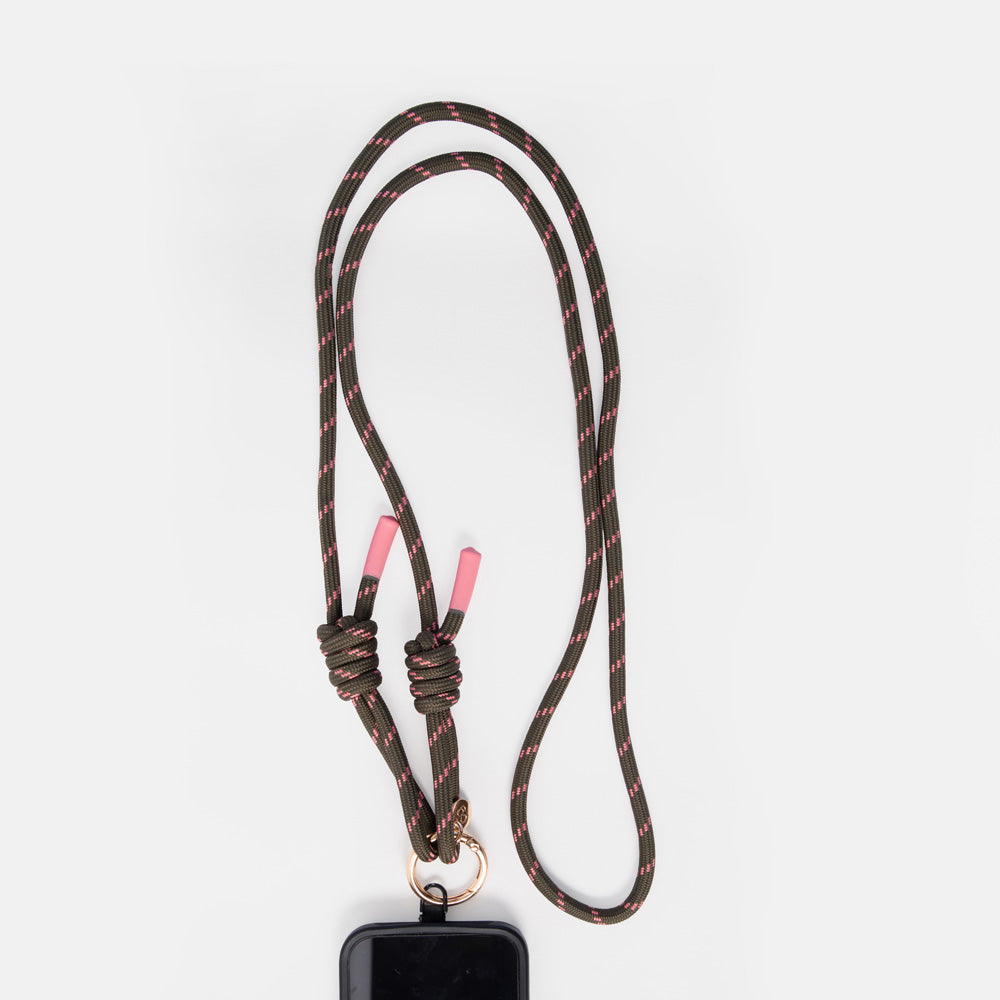A dark green cord  phone lanyard with a subtle red pattern, featuring pink-tipped knots and a gold metal ring at the bottom, holding a black rectangular device, shown on a light gray background.