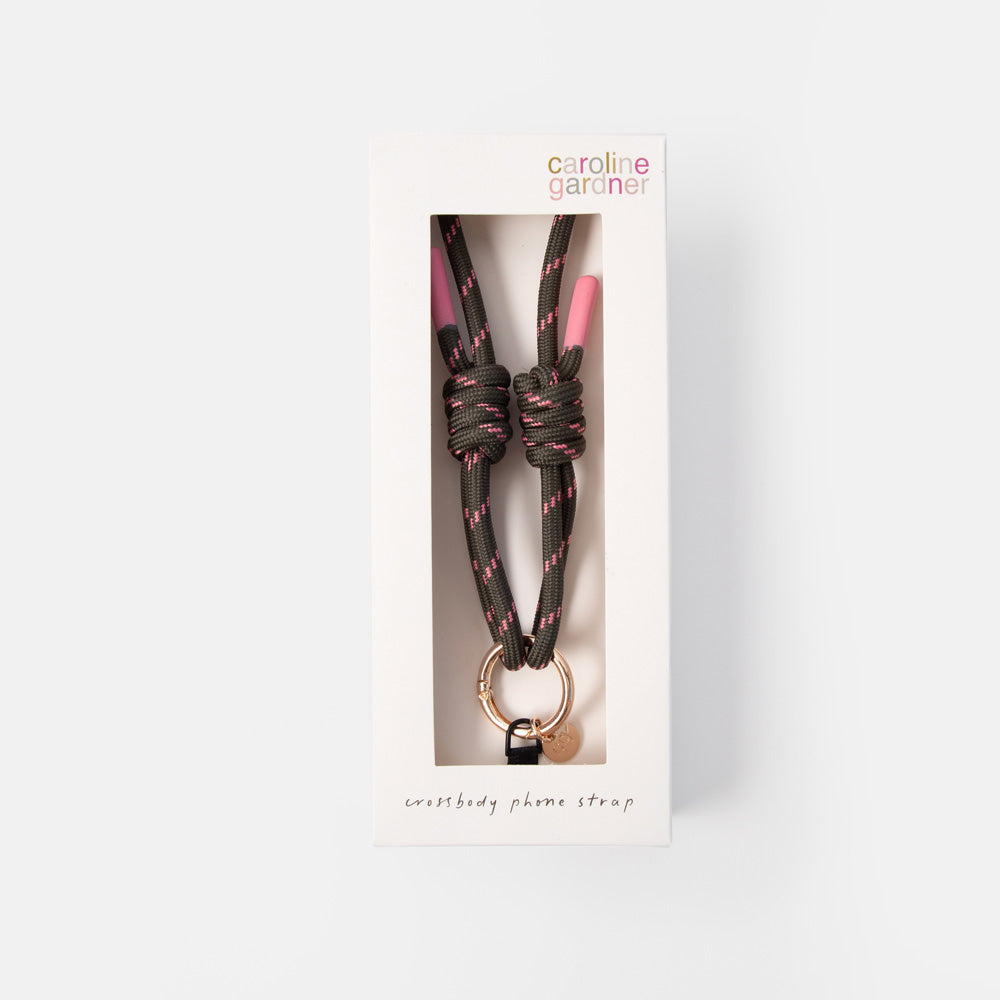 Caroline Gardner phone strap in a white retail box, featuring a dark brown and pink braided cord with a rose gold metal ring and small heart charm.
