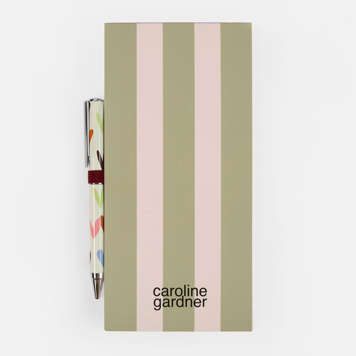 A Caroline Gardner list pad with vertical stripes in sage green, olive, and light pink, shown with a matching patterned pen on a clean white background.