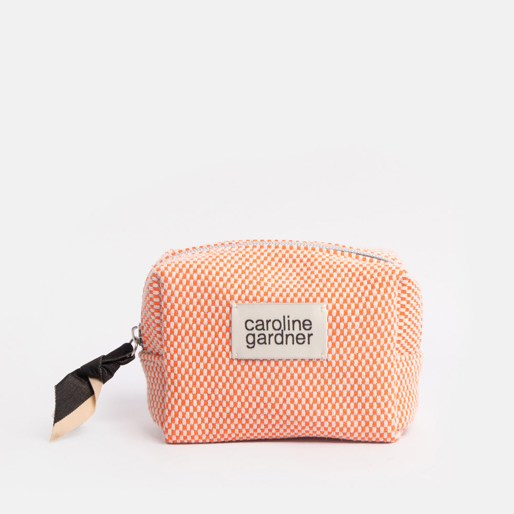 Small orange checked cosmetics bag with a black strap and 'caroline gardner' label on a white background