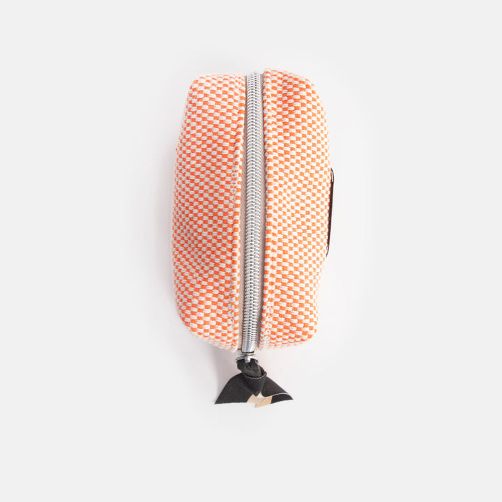 Small orange checked cosmetics bag with a black zip pull on a white background