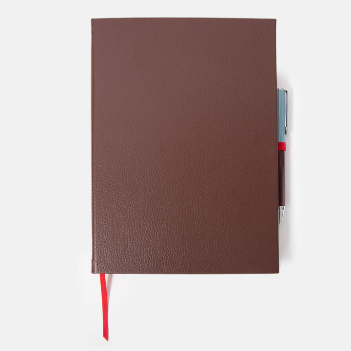 dark purple leather effect notebook with ballpoint pen set on a white background