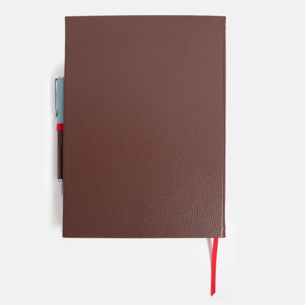 dark purple leather effect notebook with ballpoint pen set on a white background