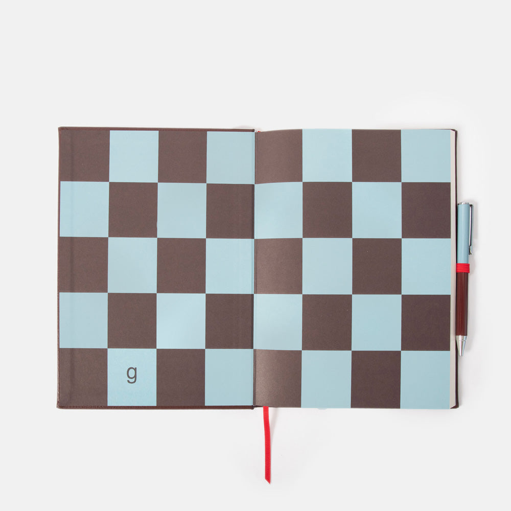 Checkered notebook inside cover page with a pen on a white background