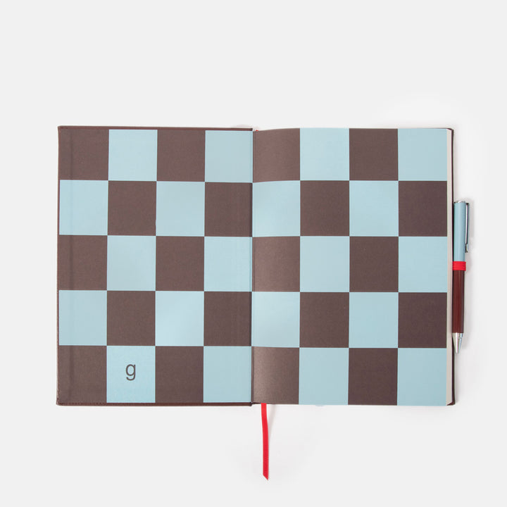 Checkered notebook inside cover page with a pen on a white background