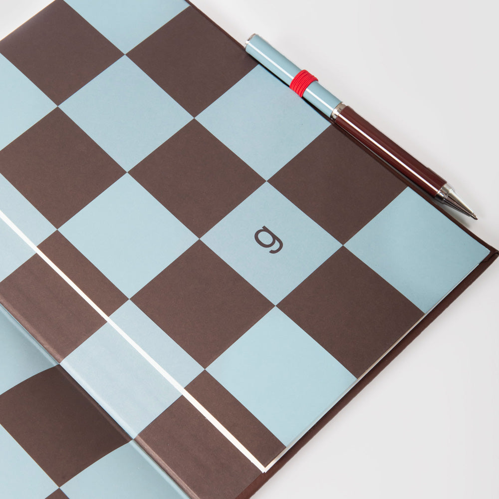 Checkered notebook inside page with a pen on a white background