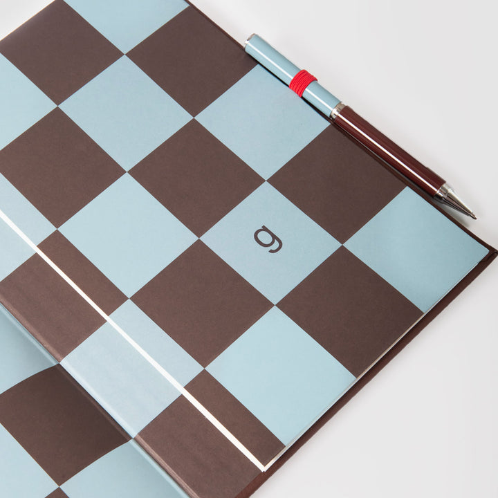 Checkered notebook inside page with a pen on a white background