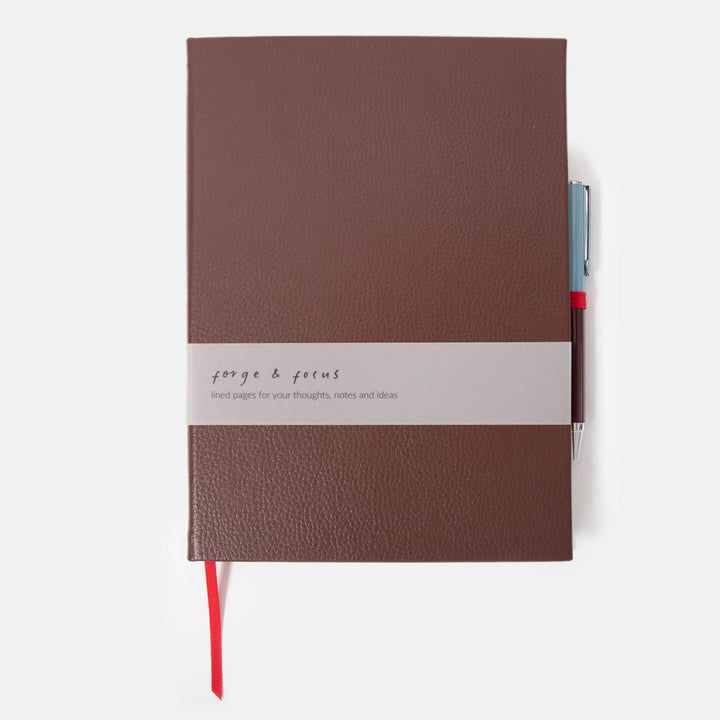 dark purple leather effect notebook with ballpoint pen set on a white background
