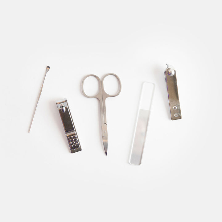 Set of nail care tools including scissors, cuticle nipper, and files on a white background