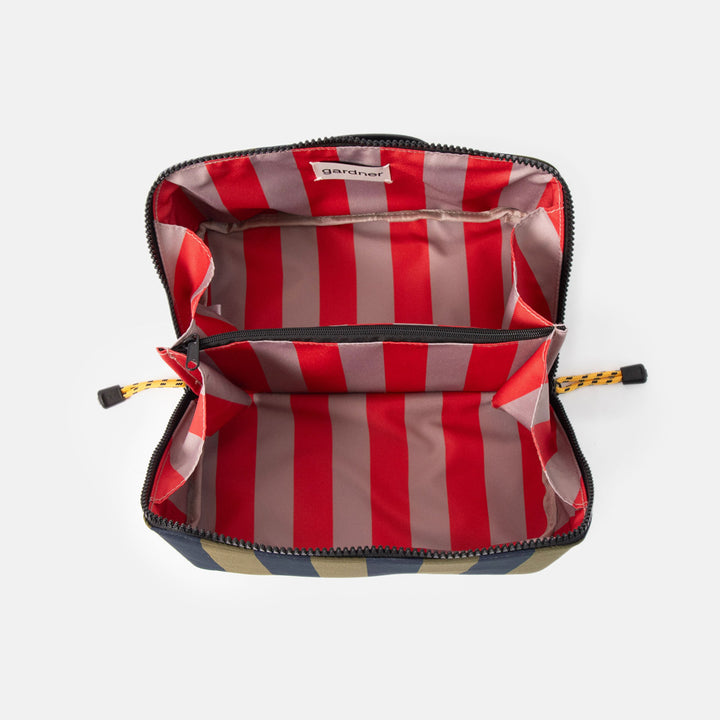 blue and green striped flat lay wash bag with diagonal zip, open showing red and sand stripe internal lining and central zipped pocket