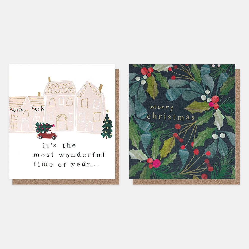 Two Christmas cards side by side on a white background. One card has houses and trees with text, the other has a wreath design with 'merry christmas' text.