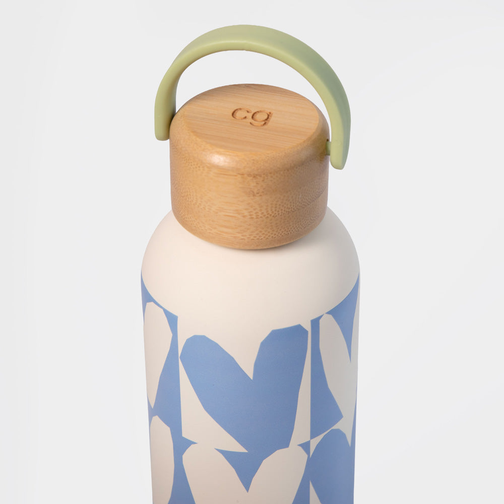 A reusable water bottle with a white body, a blue and white geometric pattern, a light wood cap, and a light green carrying loop handle, shown on a light gray background.