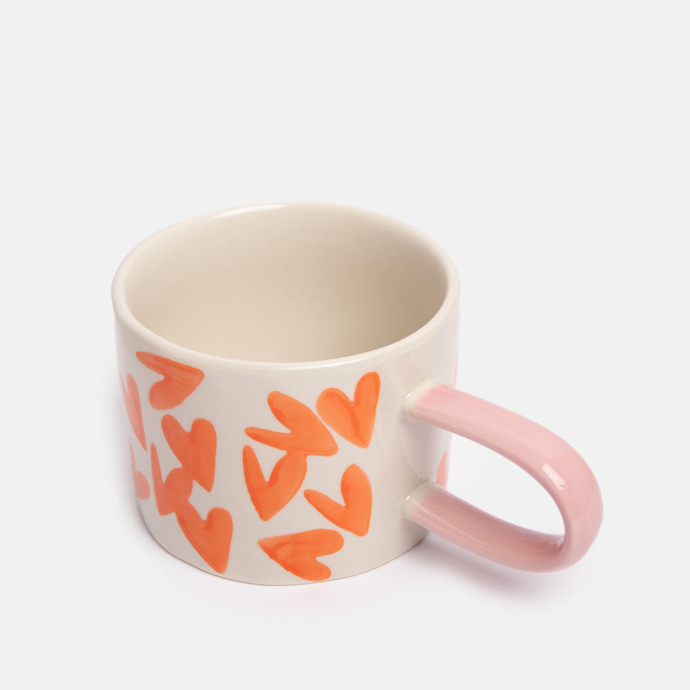 hand painted ceramic stoneware mug with bright orange hearts design and pale pink elongated handle