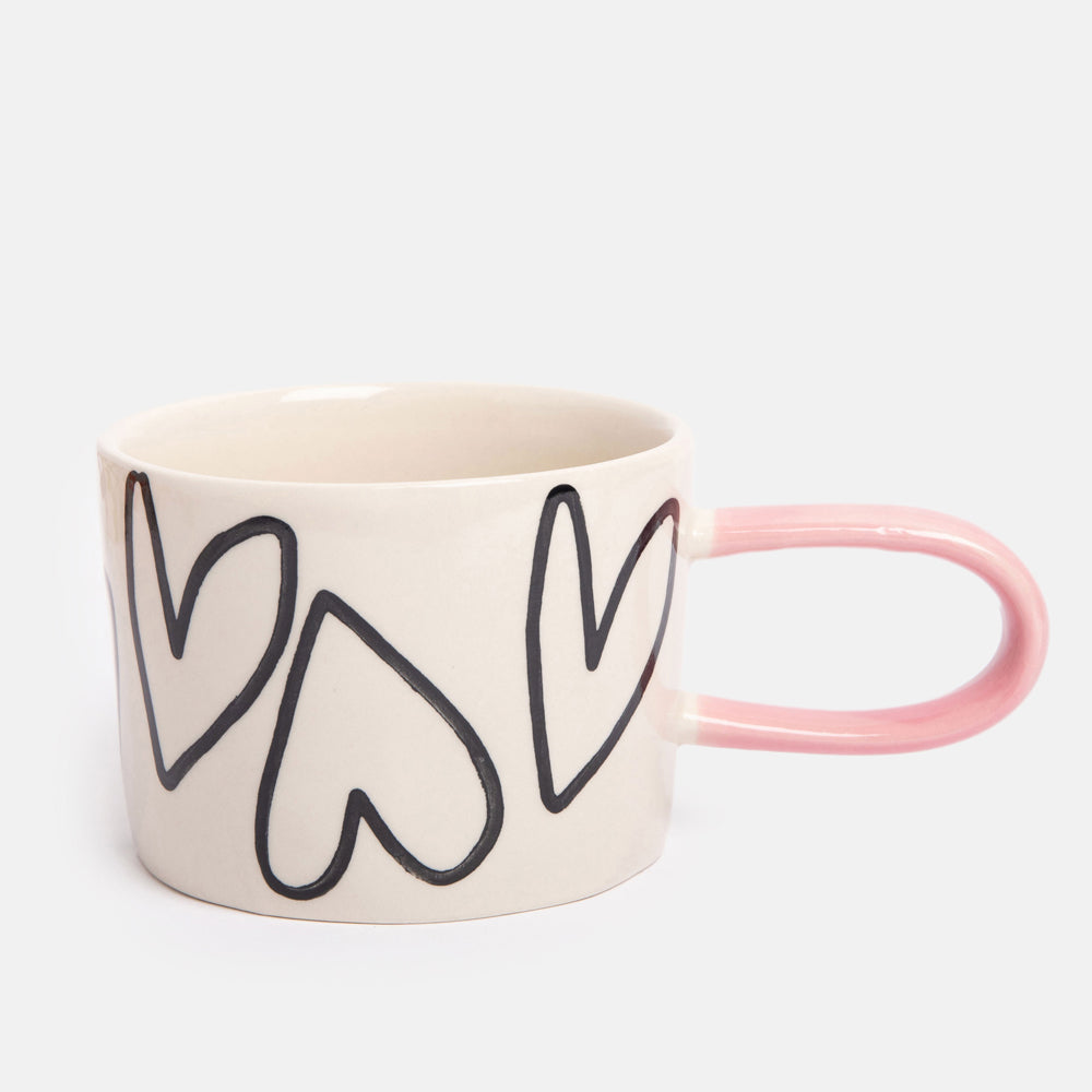 hand painted ceramic stoneware mug with monochrome hearts design and pale pink elongated handle