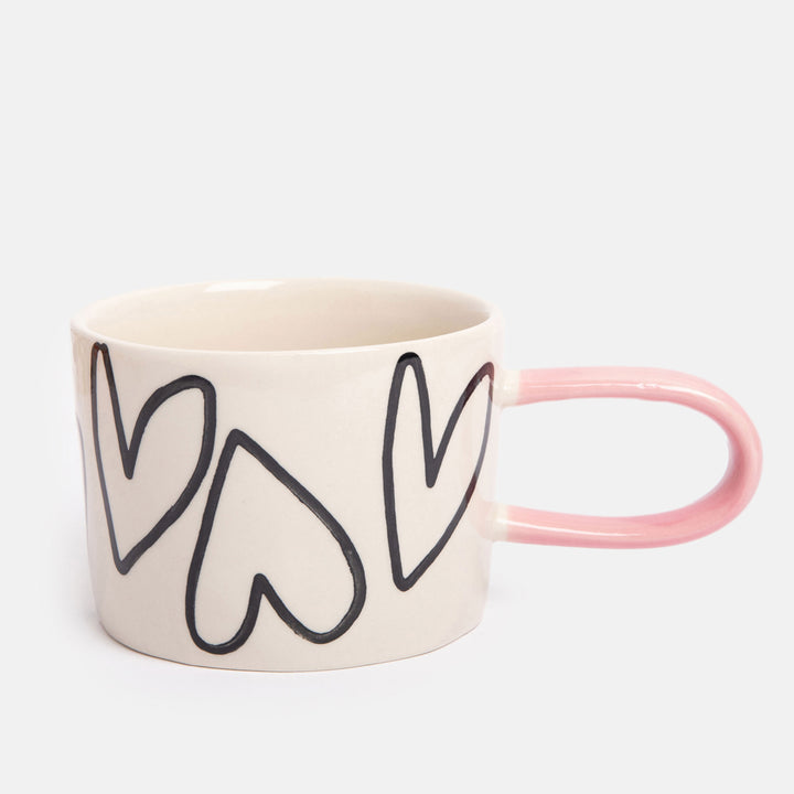 hand painted ceramic stoneware mug with monochrome hearts design and pale pink elongated handle