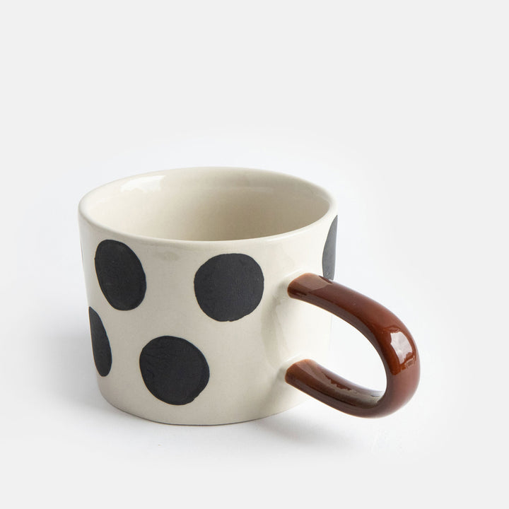 hand painted ceramic stoneware mug with big black dots design and a brown elongated handle