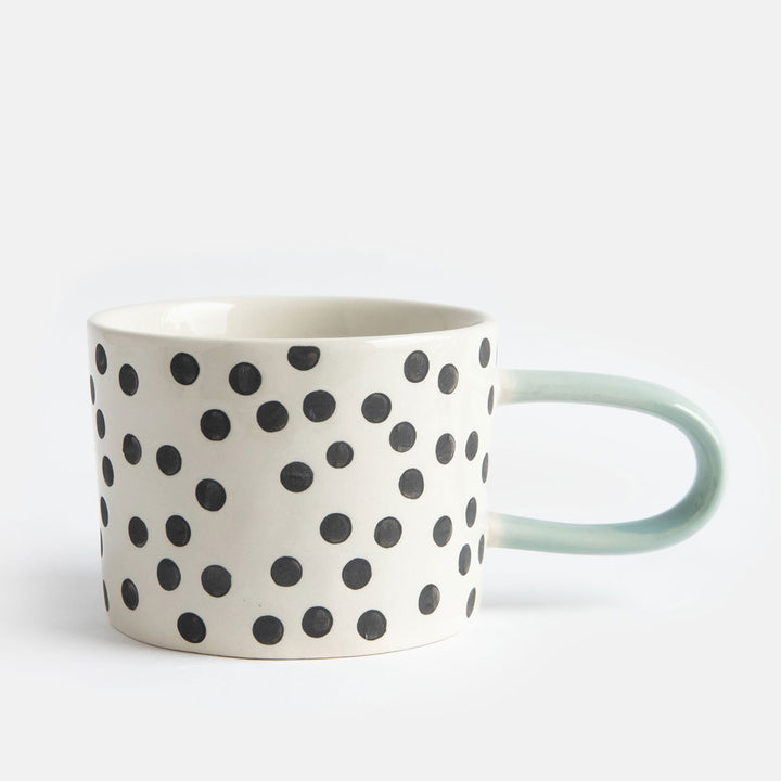 hand painted ceramic stoneware mug with small black dots design and a light blue elongated handle