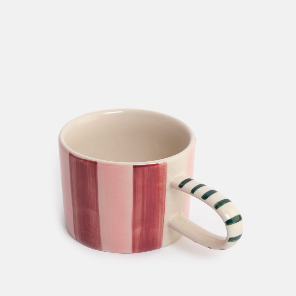 A ceramic mug with a cream-colored interior and exterior, featuring vertical pink and burgundy stripes on the outside, and a handle decorated with dark green diagonal stripes.