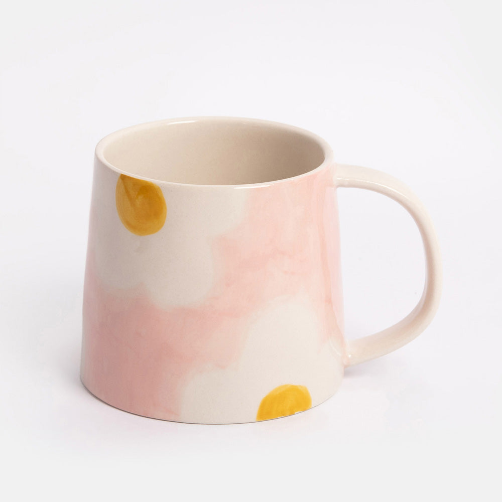 light pink mug with white and yellow flower design on a light grey background