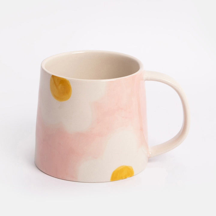 light pink mug with white and yellow flower design on a light grey background