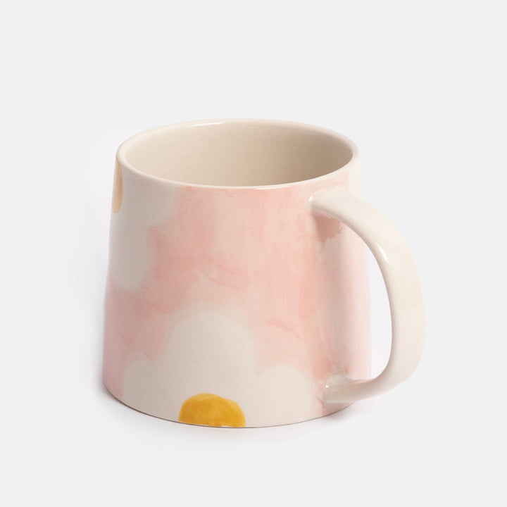 light pink mug with white and yellow flower design on a light grey background