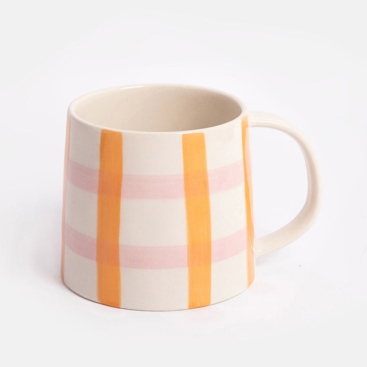 mug with a pink and orange check design on a light grey background
