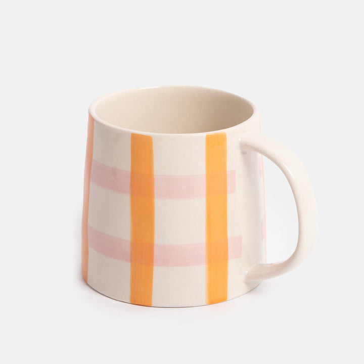 mug with a pink and orange check design on a light grey background