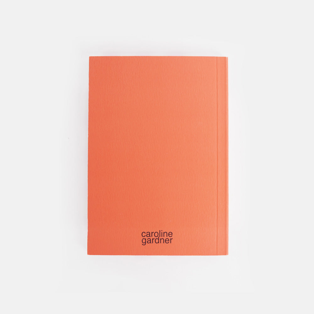 Orange notebook with 'caroline gardner' branding on a white background