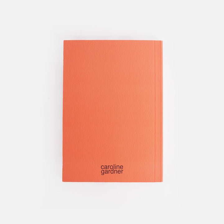Orange notebook with 'caroline gardner' branding on a white background