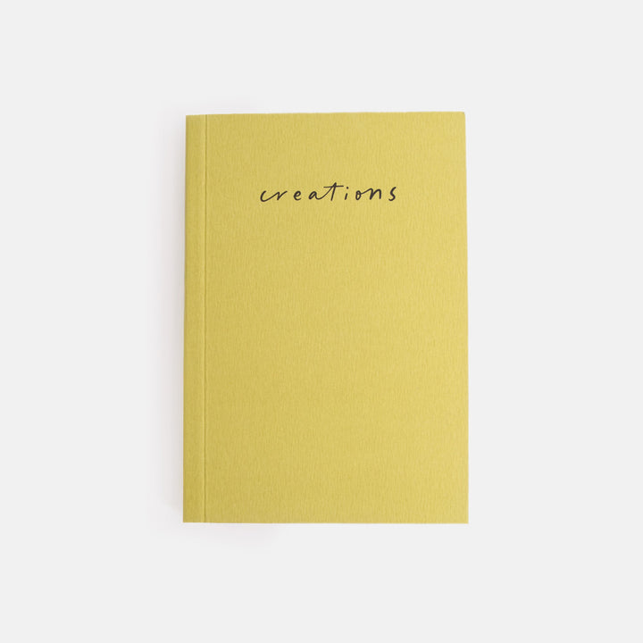green notebook with 'creations' text on a white background
