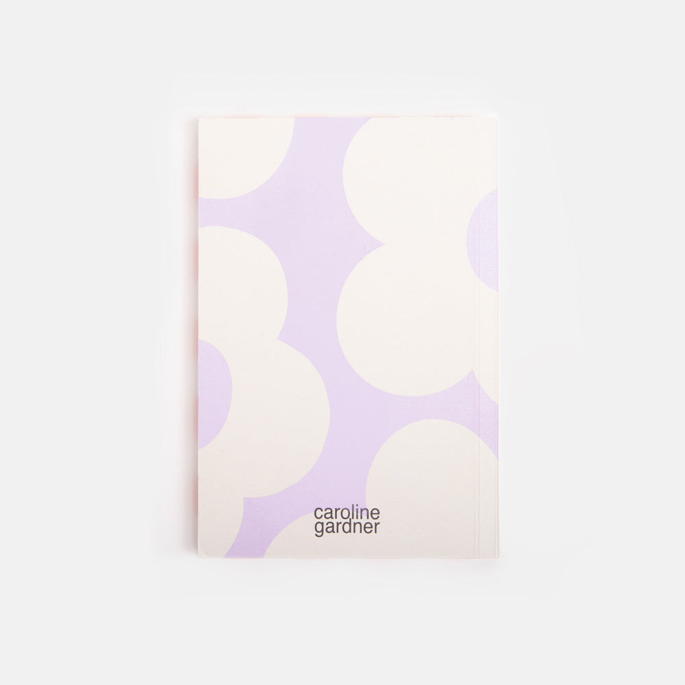lilac notebook with white flower design and 'caroline gardner' branding