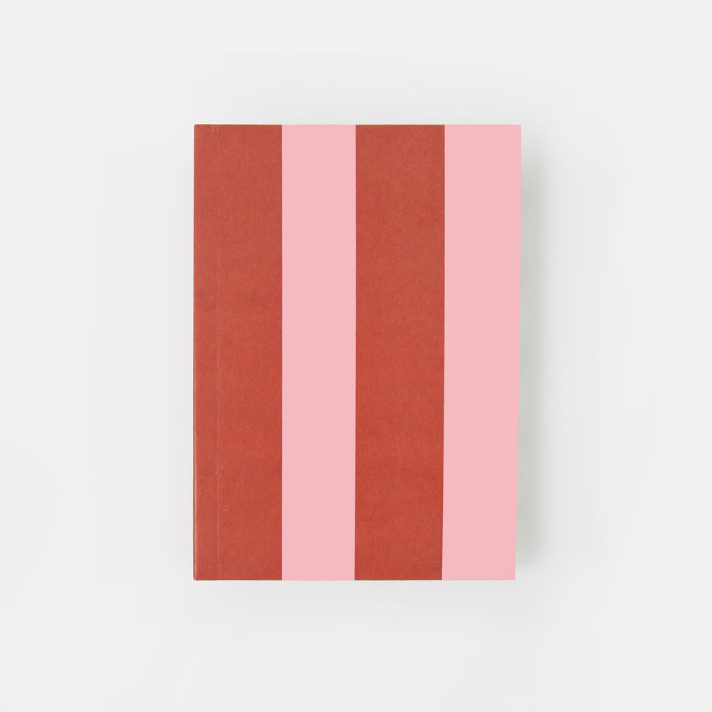A hardcover notebook with a minimalist striped cover featuring alternating vertical bands of terracotta red and light pink, set against a clean white background.