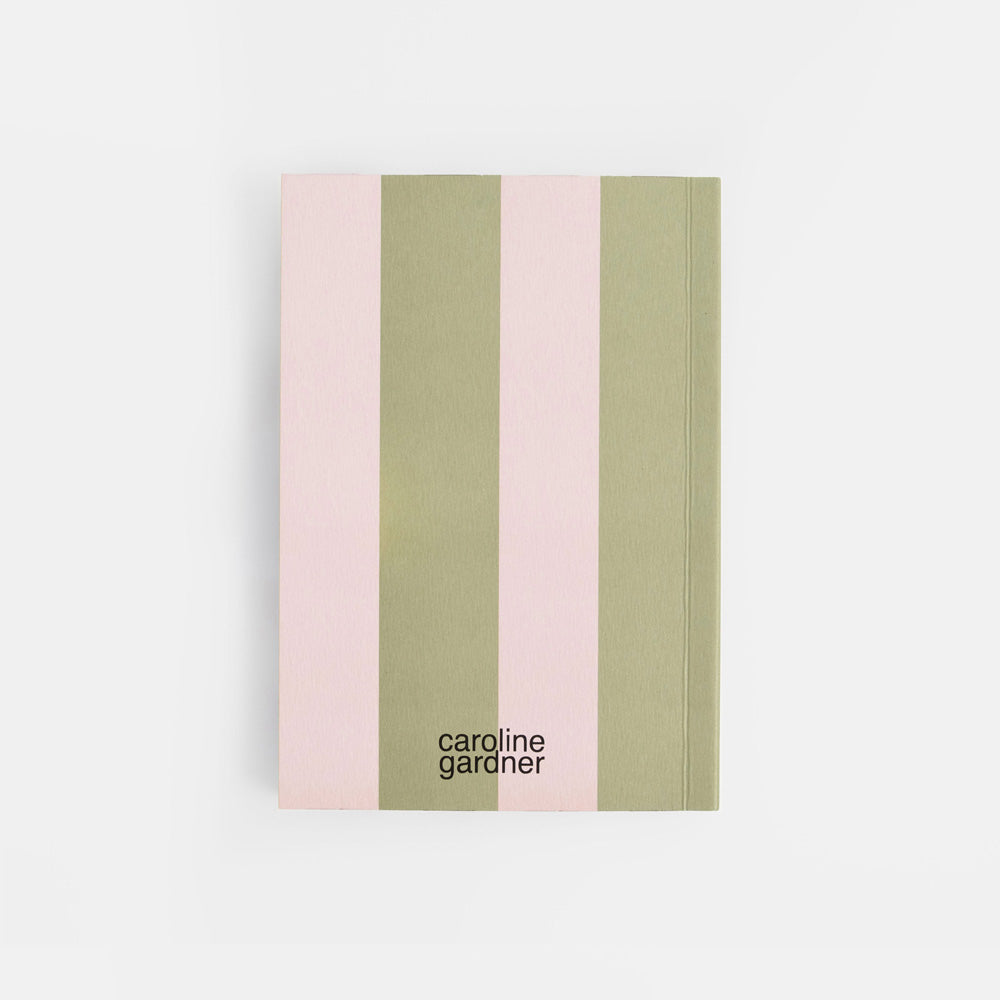 A notebook with vertical stripes in light pink and sage green, featuring the black text 'caroline gardner' near the bottom, set against a clean white background.