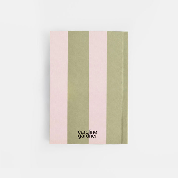 A notebook with vertical stripes in light pink and sage green, featuring the black text 'caroline gardner' near the bottom, set against a clean white background.