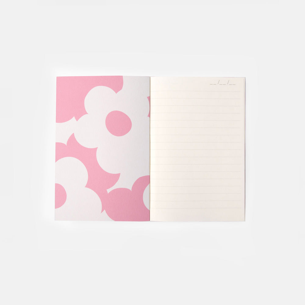 An open notebook or journal with a pink and white floral pattern on the left page and lined blank writing space on the right page, photographed on a clean white background.