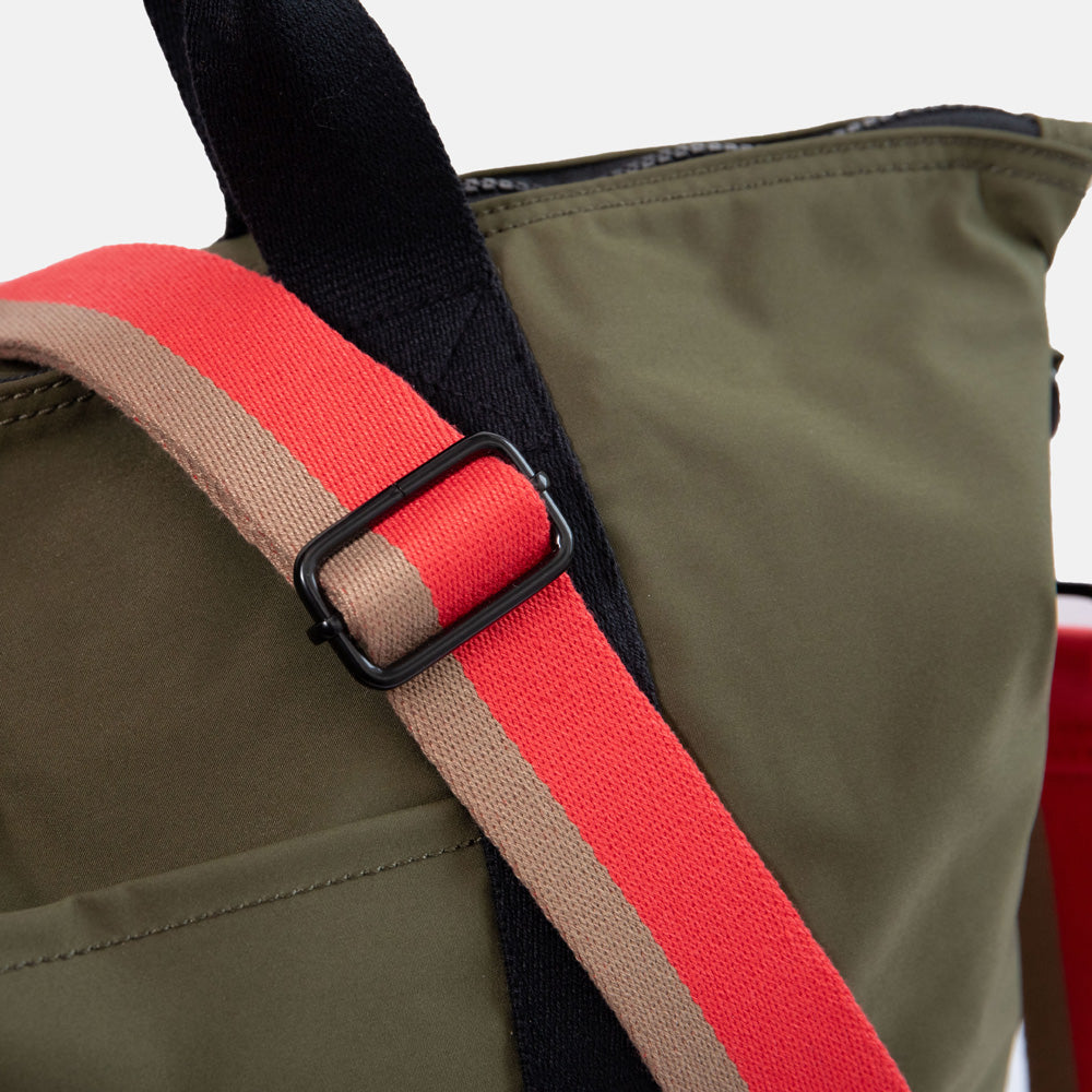 close up of dark green weekend travel bag with black grab handles and a red & sand stripe shoulder strap